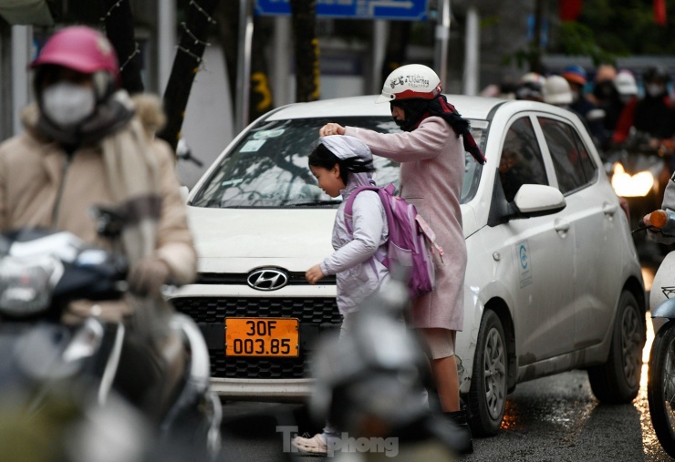 Bố mẹ đưa con đi học vào sáng sớm ngày hôm nay đều mặc áo ấm cho con khi đến trường.