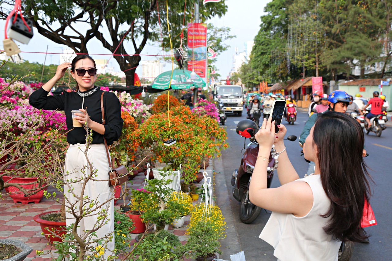 Chị Trần Thuý Ngân và Đào Cẩm Tú thích thú “check in” tại chợ hoa “trên bến dưới thuyền”. “Hôm nay 2 chúng tôi rủ nhau đi ngắm hoa, sẵn dịp mua về chưng Tết luôn. Năm nào chợ hoa này hoạt động tôi cũng đi dạo ngắm hoa vì không khí ở đây thật nhộn nhịp, khung cảnh độc đáo, nên thơ. Tầm khoảng 29-30 Tết, thuyền hoa đậu kín bến này thấy rất đẹp. Tôi thấy giá hoa năm nay cũng hợp lý, nên nhất định sẽ mua một vài chậu về chưng cho công ty và tại nhà”, chị Ngân chia sẻ.