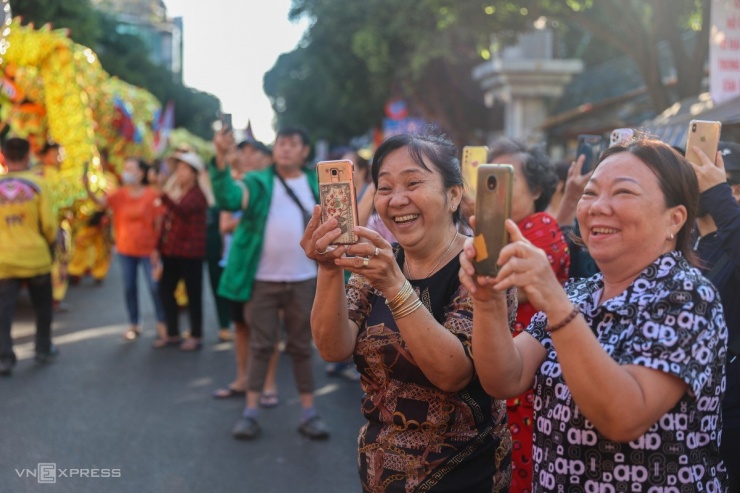 Bà Như Loan, 56 tuổi (góc phải), hào hứng quay lại cảnh đoàn người đi qua. "Với người Hoa, ông Quan Công được xem như vị thánh. Sau khi xong phần diễu hành, tôi sẽ đến hội quán thắp nhang cho ông, mong may mắn trong năm mới", bà nói.