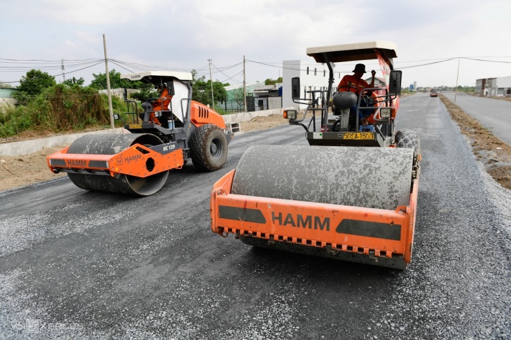 Công nhân rải đá, thảm nhựa một đoạn đường song hành đoạn đi qua huyện Bình Chánh.