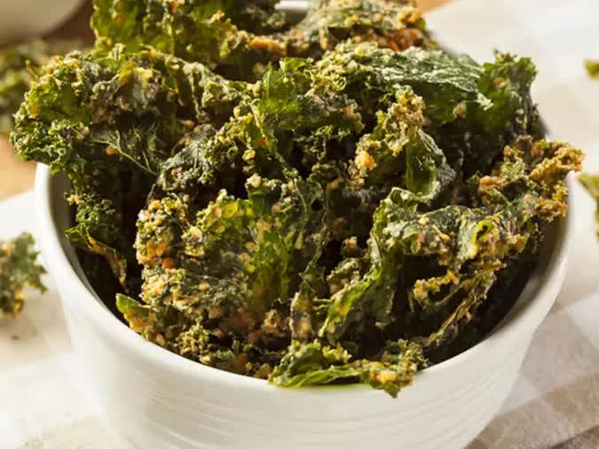 Snack cải kale: Một cách “biến tấu” độc đáo bạn nhất định nên thử nếu đang lăn tăn chưa biết cải xoăn kale làm món gì ngon đó chính là snack cải kale (kale chips). Rửa sạch từng lá cải kale, sau đó ngâm nước muối loãng khoảng 15 – 20 phút. Dùng dao khứa theo chiều dọc, chỉ giữ lại phần lá, bỏ phần cọng cứng. Tiếp tục cắt nhỏ lá thành miếng vừa ăn. Ướp lá rau cải kale với dầu ô liu, hạt nêm, hạt tiêu và ớt bột. Xếp lá cải kale lên khay nướng, đem nướng giòn ở nhiệt độ 180 độ C khoảng 15 phút là có món snack cải kale.