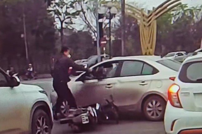 Hình ảnh người đàn ông đi xe máy cầm mũ bảo hiểm đập vỡ kính xe ô tô. Ảnh cắt từ video
