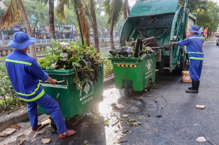 Ông Phạm Văn Tỉnh (phải) đổ rác vào xe ép. Ông cho biết, bình thường cả tuyến kênh nếu vớt sạch thì chỉ cần 4 chuyến xe. Tuy nhiên riêng đoạn kênh này từ hôm qua đến nay đã mất 5 chuyến xe chở rác đến điểm tập kết.