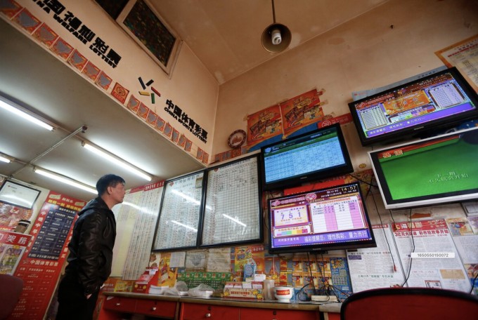 Một khách hàng nhìn vào màn hình hiển thị thông tin xổ số tại một cửa hàng bán vé số ở Thượng Hải, Ảnh minh họa: REUTERS