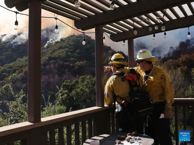 Các lính cứu hỏa quan sát cháy rừng trên đỉnh một ngọn đồi ở hạt Los Angeles hôm 11-1. Ảnh: THX