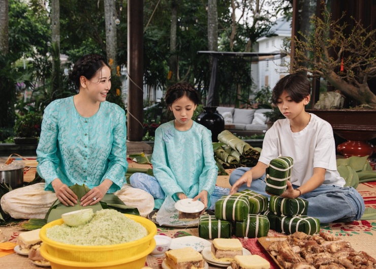 Hai con của hoa hậu là Vương Khôi (bìa phải) và Viann (giữa) cũng hào hứng học cách gói bánh chưng từ mẹ.