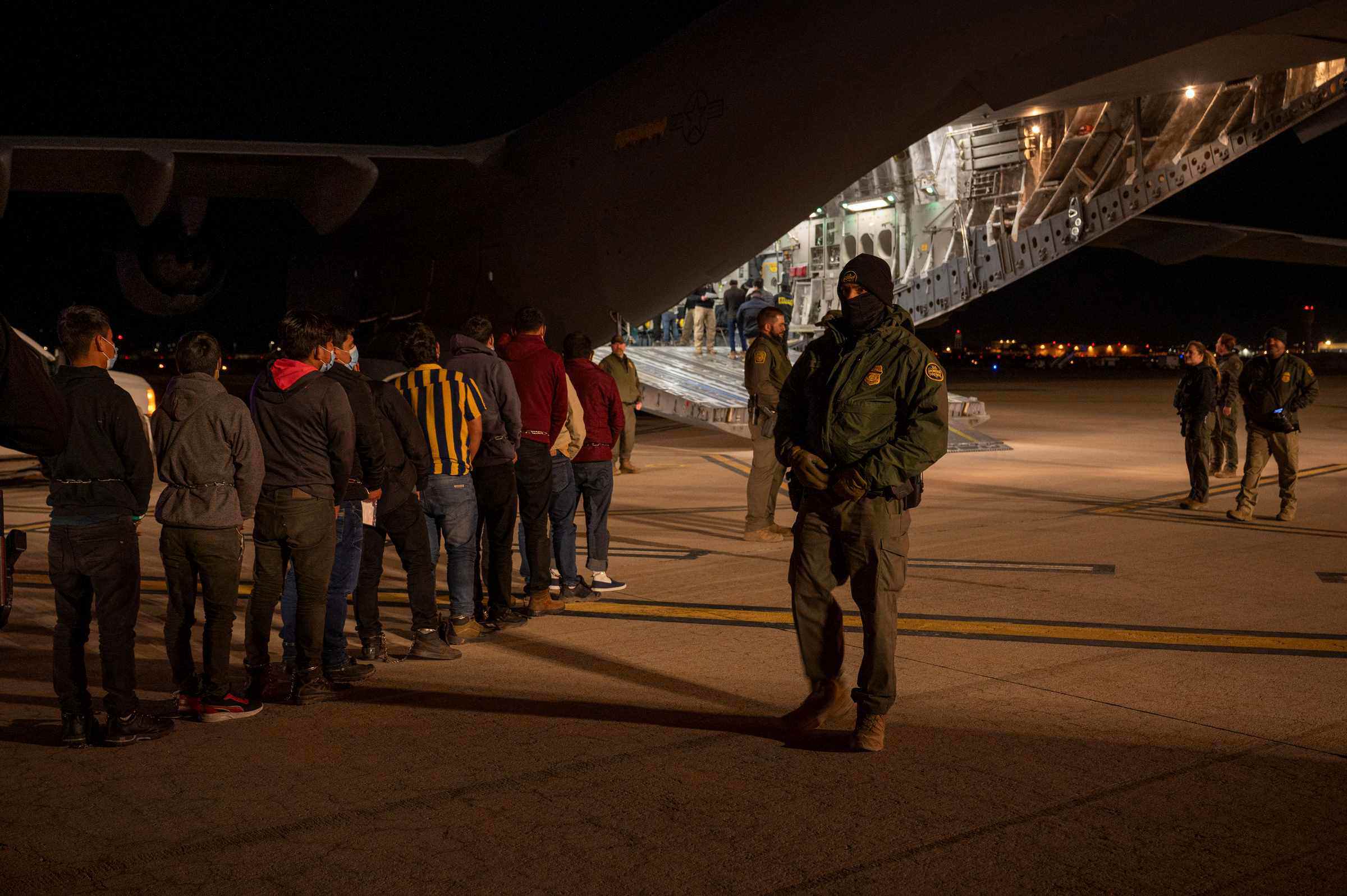 Người di cư bị áp giải lên máy bay C-17 (ảnh: Reuters)