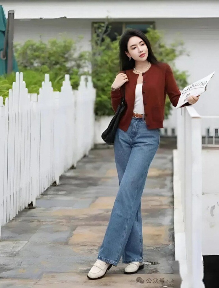 Mặc áo len đỏ tía ấm áp kết hợp với quần jeans cạp cao, tạo nên cảm giác cổ điển mạnh mẽ. Đôi giày lười màu trắng tạo thêm nét nhẹ nhàng cho sự kết hợp ấm áp và thoải mái này.