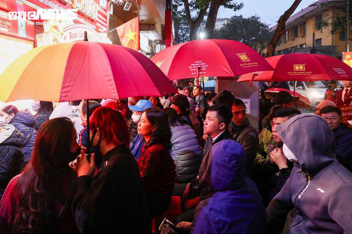 Khoảng 6h, Hà Nội xuất hiện mưa nhẹ song người dân vẫn kiên nhẫn che ô, xếp hàng dưới mưa chờ đến lượt vào mua vàng.