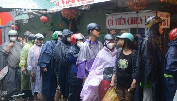 Dòng người xếp hàng dưới mưa chờ tới lượt mua hàng phía ngoài tiệm.