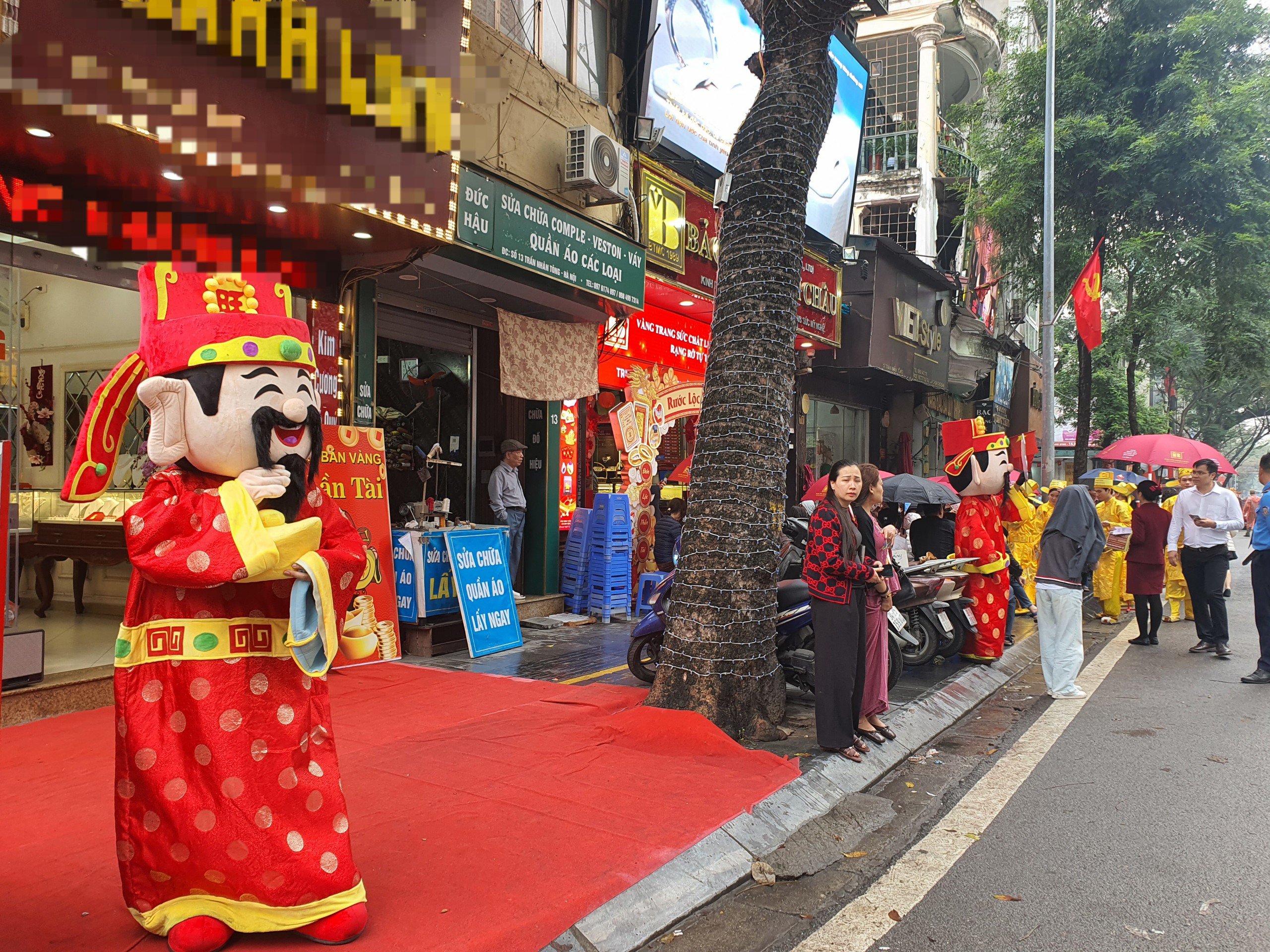 Trước cửa các cửa hàng kinh doanh vàng, hàng chục nhân viên mặc quần áo đóng giả Thần Tài đứng mời khách.