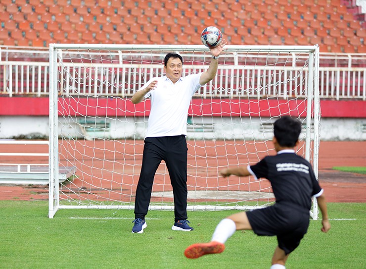 HLV thủ môn Lee Quon Jae đứng trong khung thành bắt bóng cho các cầu thủ nhí tập dứt điểm.