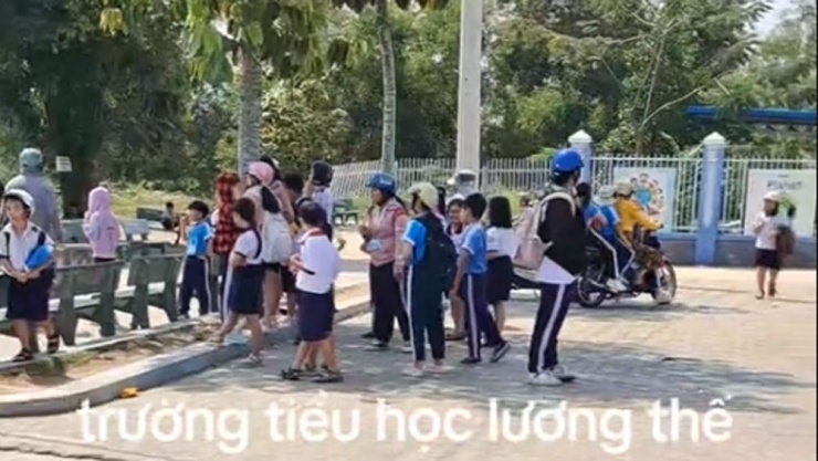 Học sinh đứng ngoài cổng chờ phụ huynh đến đón (ảnh cắt từ video chia sẻ mạng xã hội)