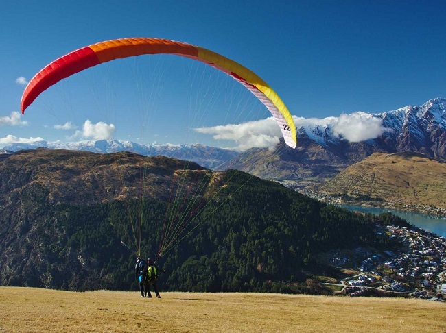 Chơi dù lượn trên các ngọn núi và ao nước bao quanh thành phố đẹp như tranh vẽ của Queenstown, New Zealand.