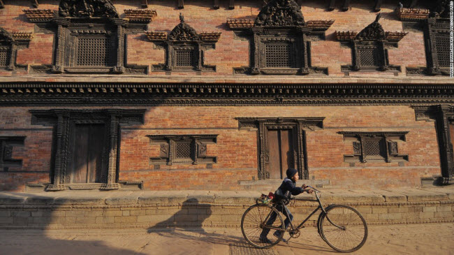 Cậu bé dắt xe đạp qua quảng trường cổ Bhaktapur Durbar ở Kathmandu, Nepal.