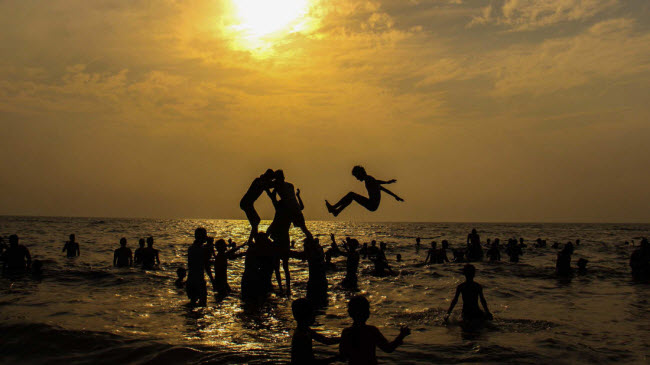 Nhóm du khách tạo hình kim tự tháp trên nền trời hoàng hôn tại bãi biển Juhu Beach ở thành phố Mumbai, Ấn Độ.