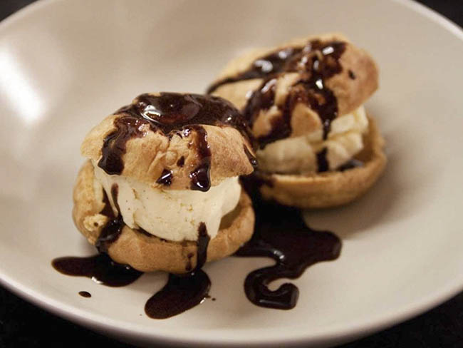 8. Profiteroles là những chiếc bánh su kem nhỏ chứa đầy kem vani và lớp socola bên trên.