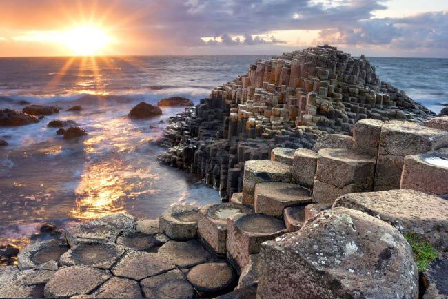 Giant&#39;s Causeway, Bắc Ireland: Vùng bờ biển thuộc hạt Altrim, Bắc Ireland, Vương quốc Anh. Bờ biển này thu hút rất đông khách du lịch và các nhà nghiên cứu đến đây bởi tại đây có khoảng 40.000 cột bazan khổng lồ màu đen được xếp ngay ngắn, kết quả của một vụ phun trào núi lửa cổ xưa cách đây 50-60 triệu năm.