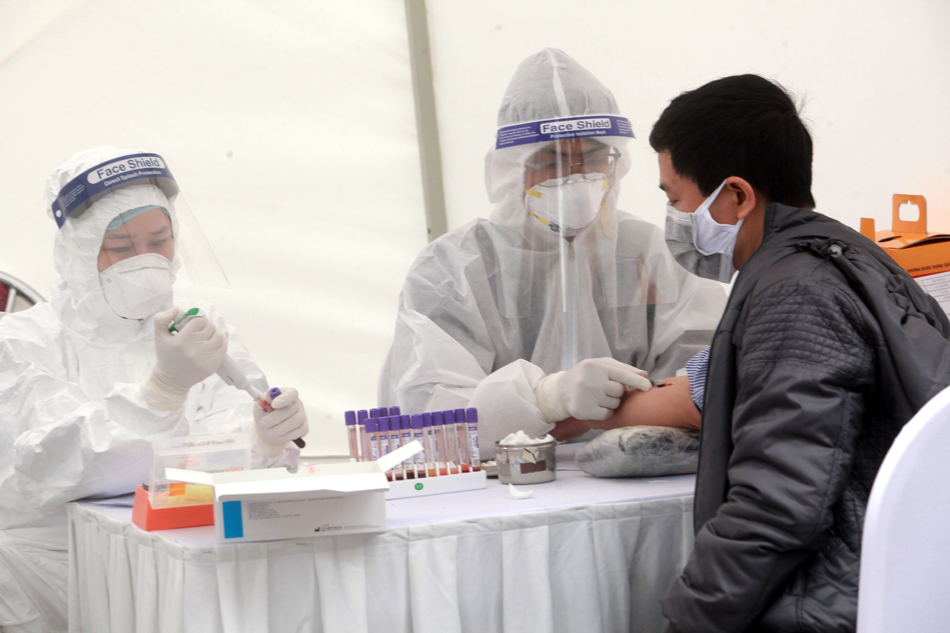 Nhân viên y tế lấy mẫu&nbsp;xét nghiệm nhanh sau khi người dân kê khai thông tin cá nhân. Ảnh Hồng Phú