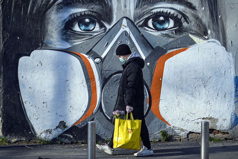 Một người đeo khẩu trang đi bộ qua bức&nbsp;vẽ hình mặt nạ phòng độc tại Pháp (ảnh: SCMP)