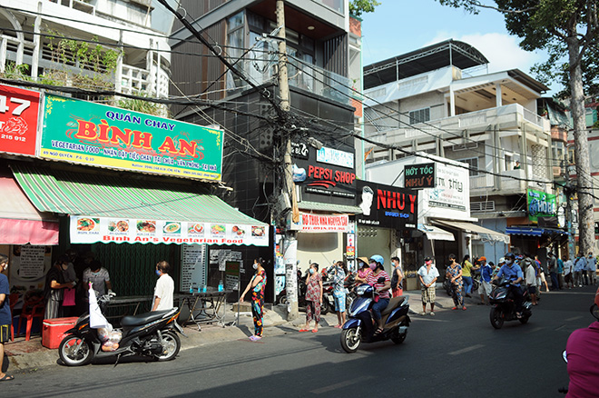 Người dân xếp hàng dài trên đường Ngô Quyền&nbsp;(phường 6, quận 10) để chờ đến lượt nhận cơm, sữa, khẩu trang, nước rửa tay miễn phí từ quán cơm chay Bình An.