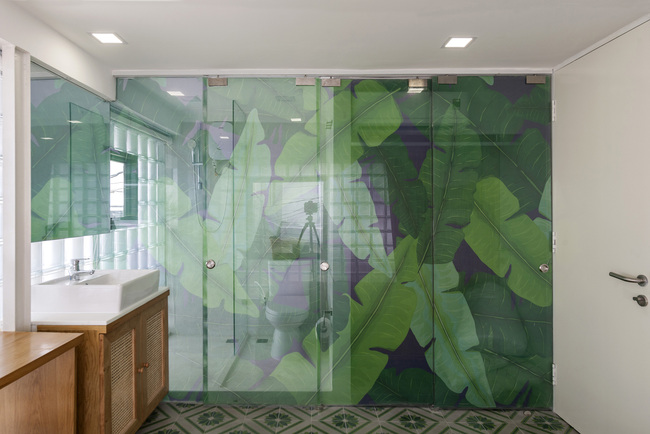Không gian này chỉ có hai màu: màu xanh lá cây của sàn xi măng truyền thống và hoa văn hình lá chuối được áp dụng trên cửa kính; và tông màu ấm trung tính của đồ nội thất bằng gỗ và trang trí nội thất mềm mại.