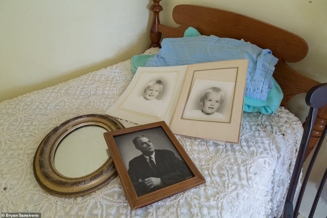 Hai bức ảnh trẻ em, một khung ảnh cũ và chiếc gương bị bỏ lại trên chiếc giường đơn.
