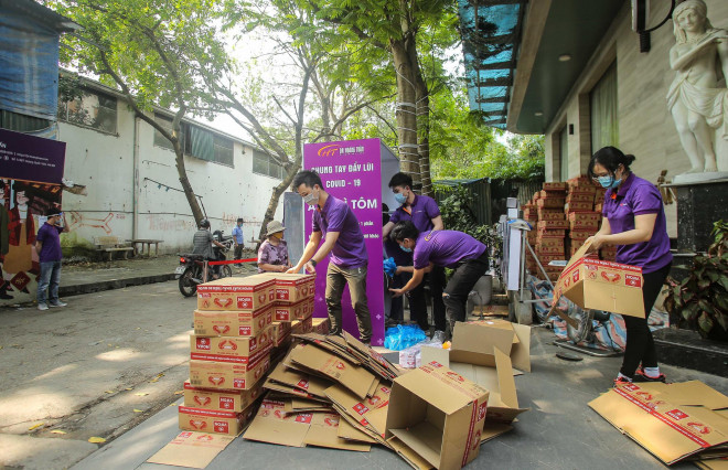 Các thành viên trong chương trình "Chung tay đẩy lùi Covid-19" đang hỗ trợ nhau để trao những phần quả thật ý nghĩa cho những người dân nghèo