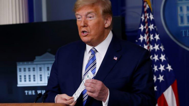 Ông Trump cầm miếng gạc xét nghiệm Covid-19 trong cuộc họp tại Nhà Trắng hôm 19-4. Ảnh: Reuters
