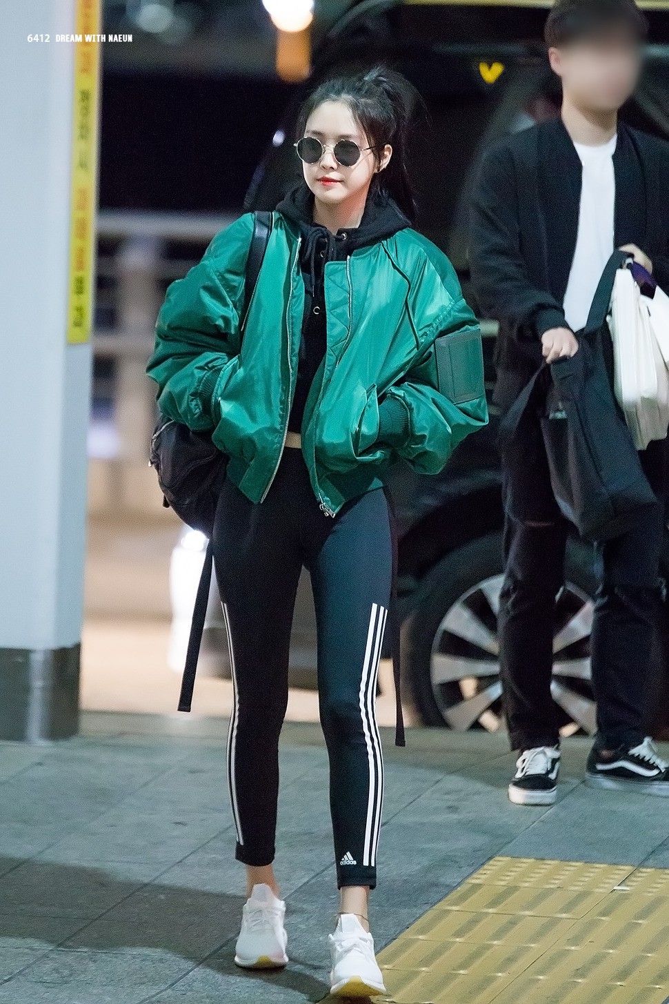 Với set đồ này, Na Eun chọn mặc áo hoodie croptop phối cùng với áo bomber. Cô mặc quần legging màu đen và kết hợp trang phục với đôi giày thể thao màu trắng.