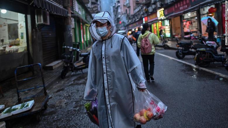 Một người đàn ông đeo khẩu trang, mặc trang phục bảo hộ đi chợ ở Vũ Hán ngày 20.4.