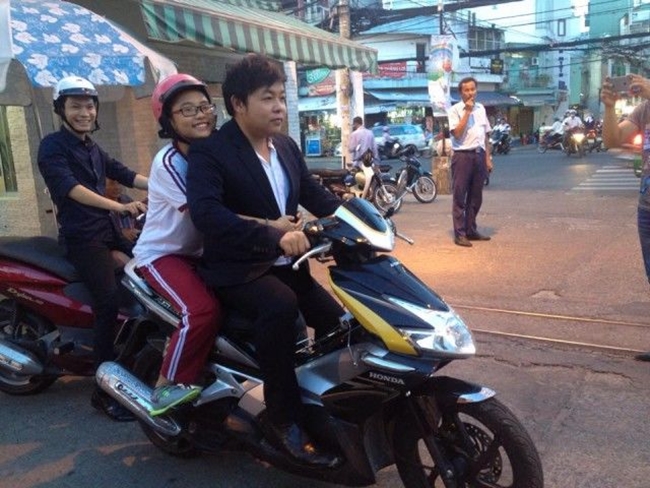 Ca sĩ Quang Lê chở "con nuôi" Phương Mỹ Chi trên chiếc xa tay ga bóng loáng thu hút sự chú ý của người dân.
