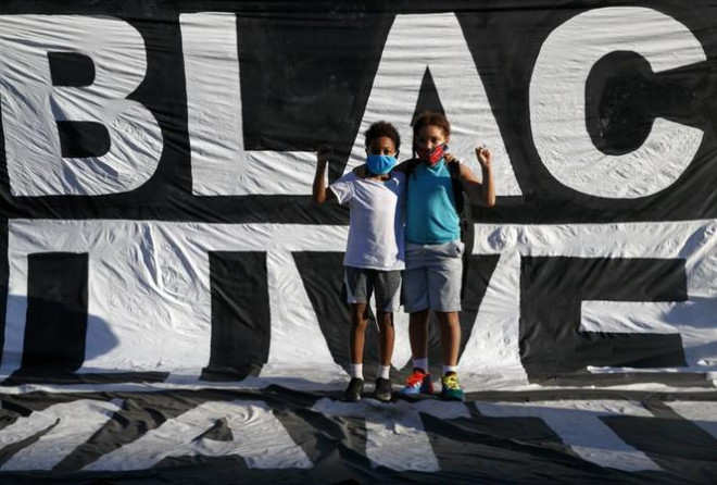 Hai cậu bé da màu đứng trước khẩu hiệu của người biểu tình căng ngoài công viên Lafayette ngày 7/6. Ảnh: AP