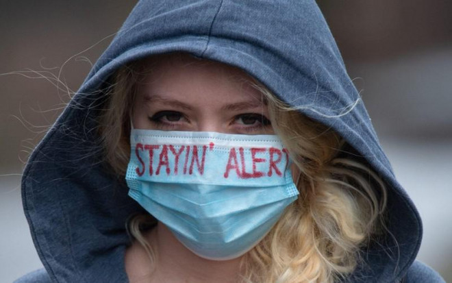 Một cô gái ở TP&nbsp;Manchester (Anh) đeo khẩu trang có dòng chữ "Hãy cảnh giác". Ảnh: TELEGRAPH/ALAMY NEWS