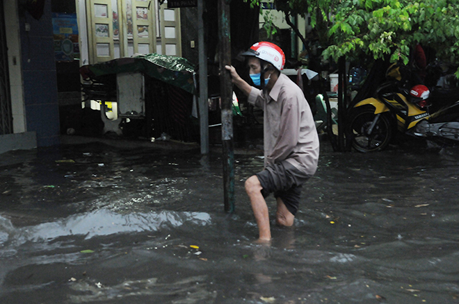 Cụ ông rà chân lội trên đường ngập vì sợ lọt hố ga