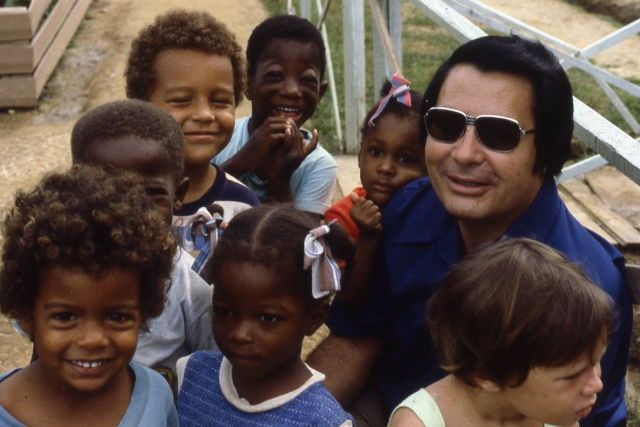 Jim Jones chụp ảnh cùng những trẻ em sống cùng ông ta ở Jonestown (ảnh: History)