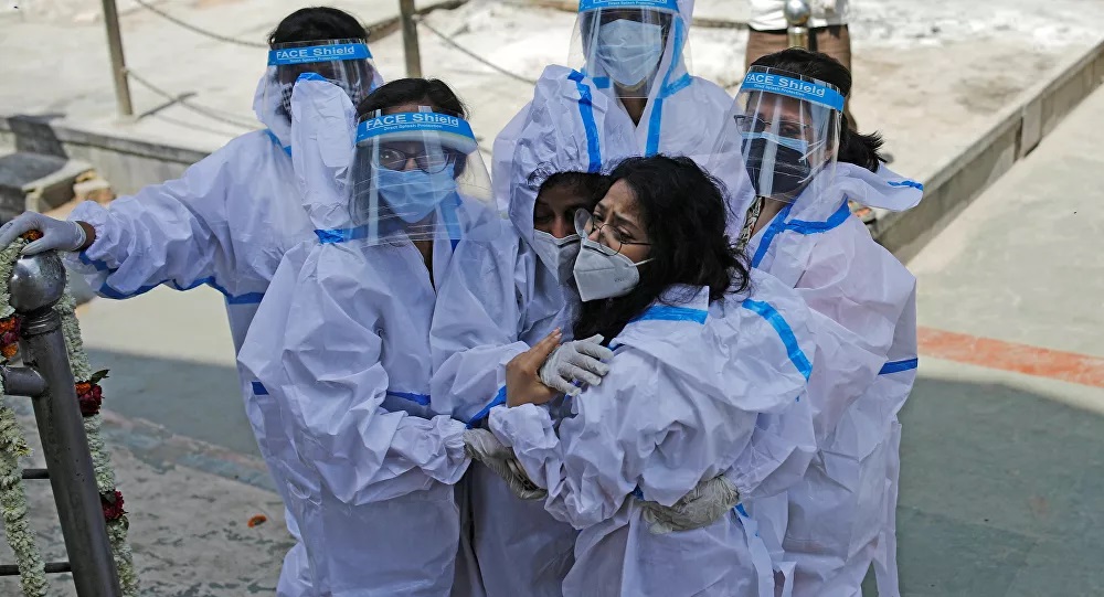 Nhóm người&nbsp;mặc đồ bảo hộ đau buồn khi một người thân tử vong vì Covid-19. Ảnh: Reuters