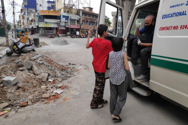 Tình nguyện viên Ahmed trò chuyện với các con trước khi lên đường đi làm tiếp. Ảnh: Reuters