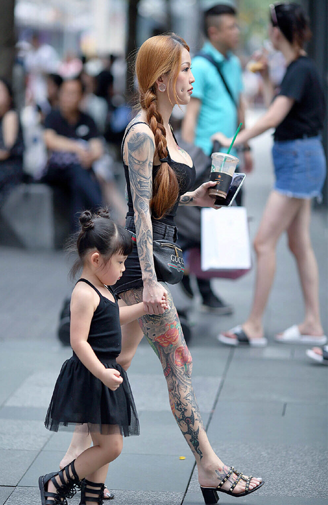 Mẹ trẻ dắt con nhỏ đi dạo phố trong bộ trang phục gây tranh cãi bao gồm áo 2 dây và quần short, tôn dáng tối đa.
