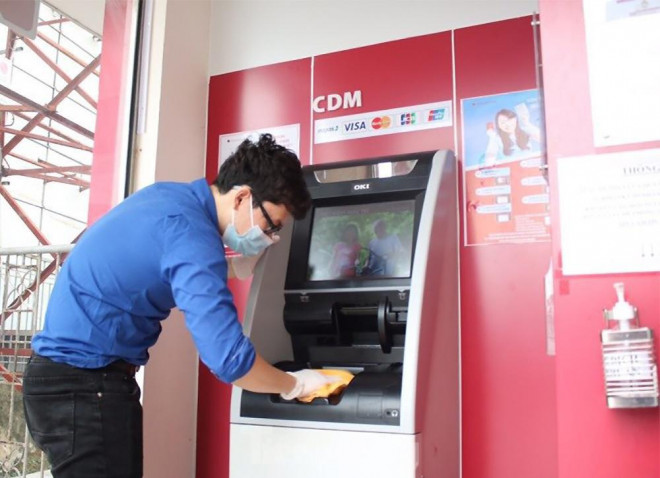 Nhân viên ngân hàng sau giờ chiều đều phải sát khuẩn máy ATM mỗi ngày.