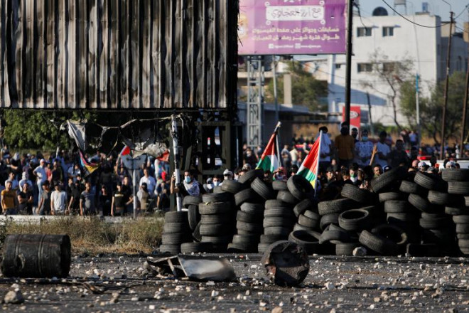 Người dân Palestine dựng rào chắn bằng lốp xe biểu tình ở Bờ Tây. Ảnh: Reuters