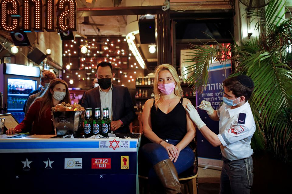 Một phụ nữ tiêm vaccine để được một đồ uống miễn phí tại một quán bar ở Tel Aviv, Israel.