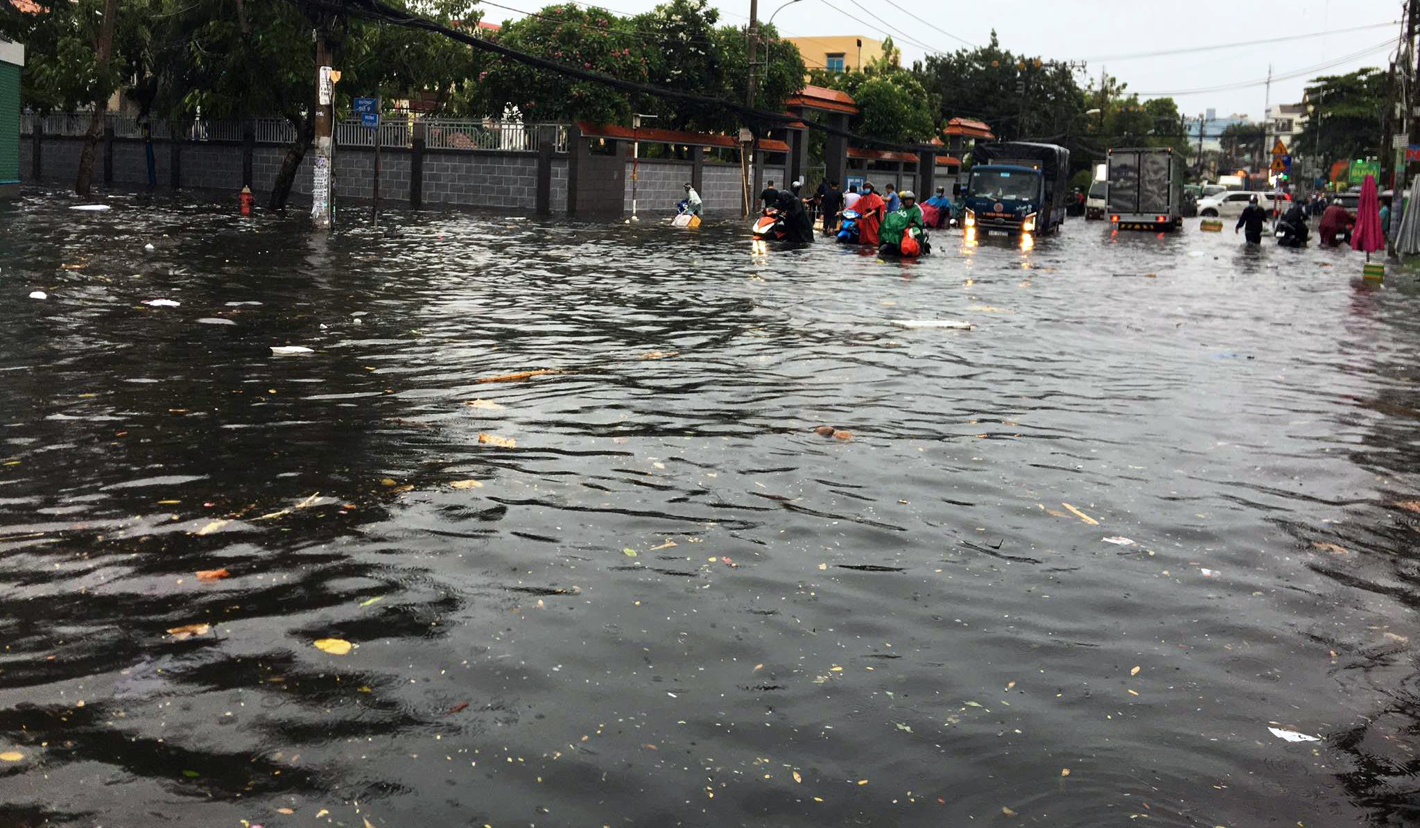 Người dân vừa dắt xe chết máy, vừa phải rà chân di chuyển trên đường ngập nước vì sợ lọt xuống ống cống, hố ga.