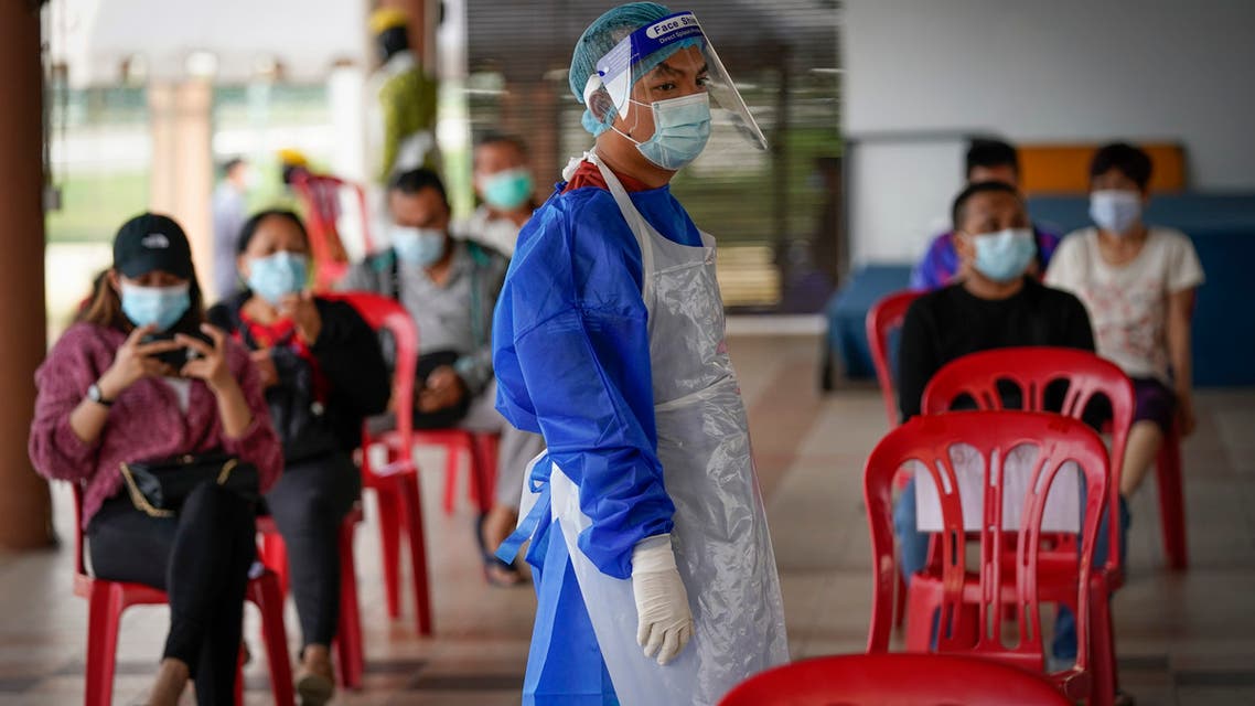 Một nhân viên y tế mặc đồ bảo hộ đứng cạnh những người chờ được xét nghiệm Covid-19 tại một trung tâm xét nghiệm tư nhân ở Malaysia. Ảnh: AP