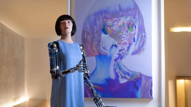Người máy Ai-Da và bức chân dung tự họa của cô tại triển lãm ở London.