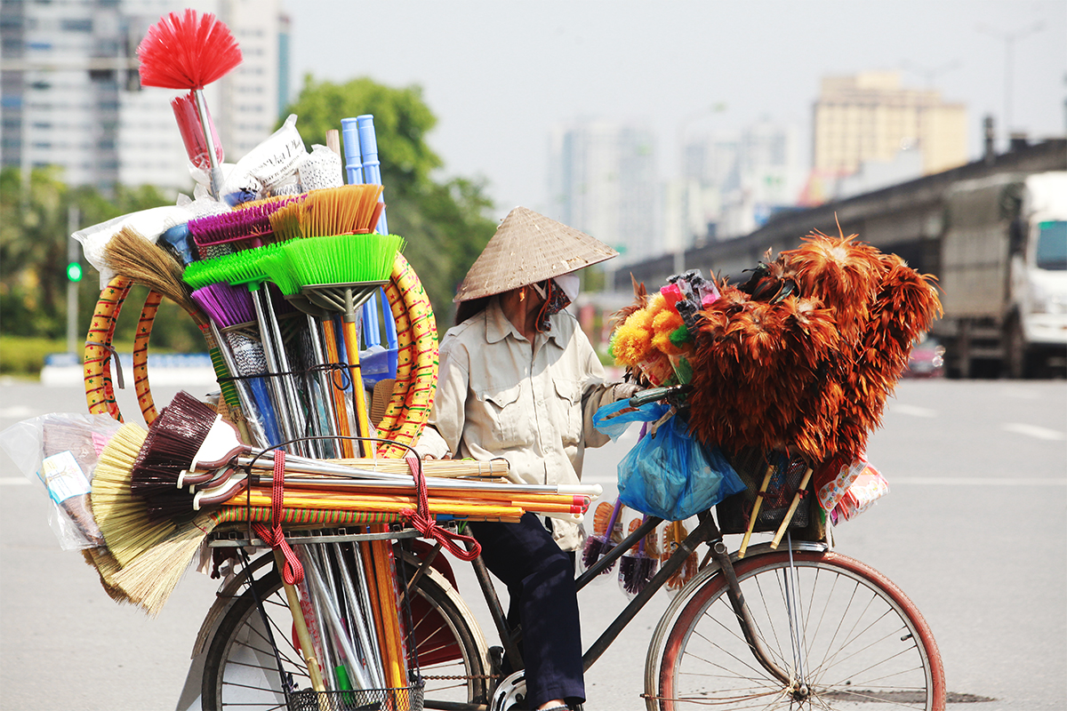 Đường phố nắng nóng, ít người đi lại nhưng những người phụ nữ đạp xe bán hàng rong vẫn “gồng mình” khắp các con phố mưu sinh trong mùa dịch.