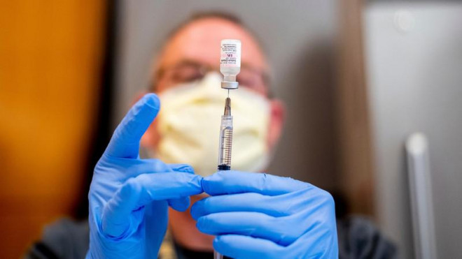 Một nhân viên y tế đang chuẩn bị lấy vaccine ngừa COVID-19 ra khỏi lọ. Ảnh: AP