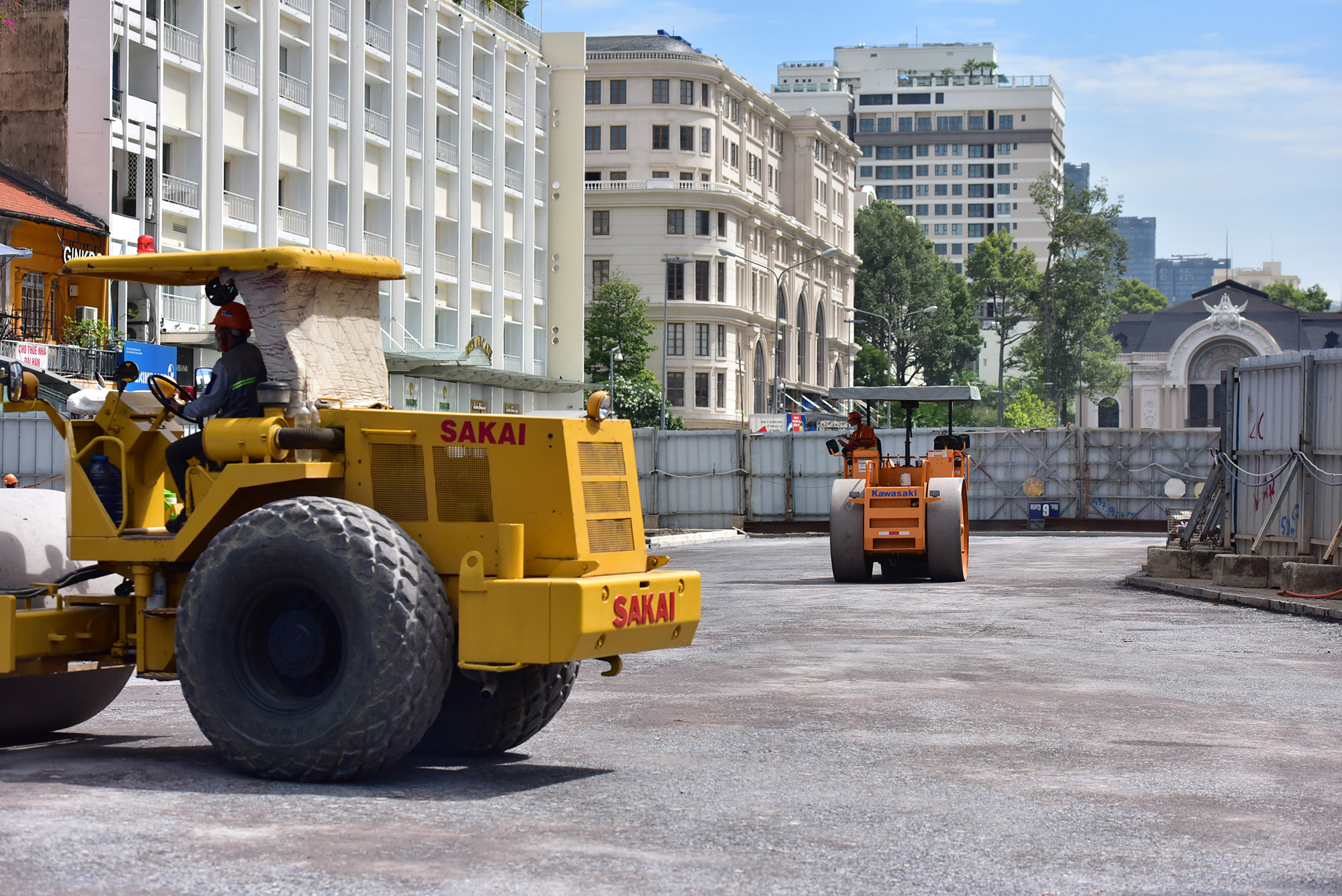 Hai chiếc xe lu đang lần lượt lu nền đá dăm để chuẩn bị trải nhựa cho mặt đường.