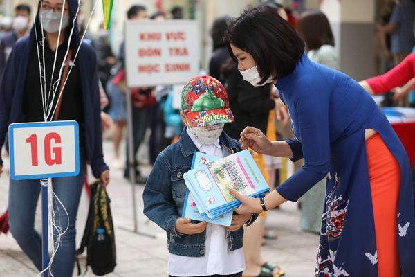 Cô Nguyễn Bích Thủy hiệu trưởng đang tự tay tặng vở cho em học sinh lớp 1 trước khi vào lớp học. Tin, ảnh: Như Ý