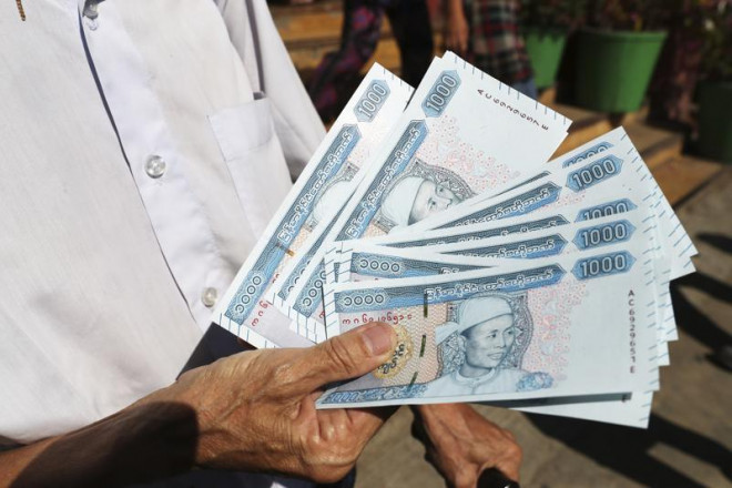 Một người đàn ông cầm các tờ tiền mới bên ngoài Ngân hàng Kinh tế Myanmar. Ảnh: AP